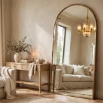 Oversized arched brass-framed floor mirror in a luxury living room